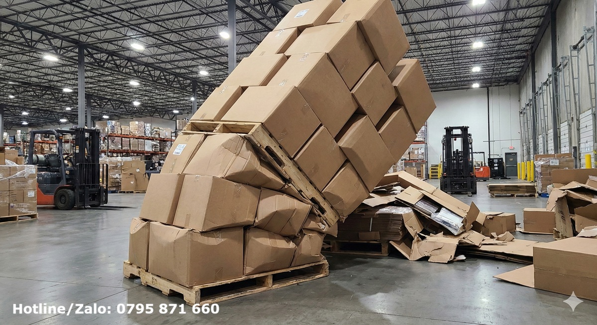 Hiện trường pallet hàng hóa bị sụp đổ trong kho do thùng carton lớp đáy bị xẹp (Buckling) vì chịu tải trọng tĩnh quá lâu.